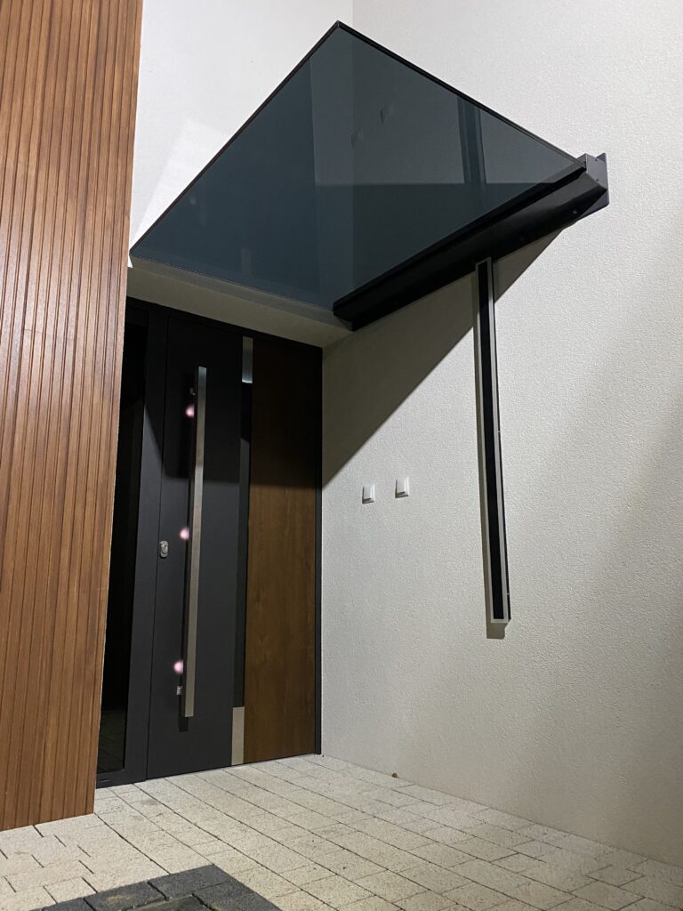 Szklane zadaszenie drzwi wejściowych z serii Prestige, minimalistyczna konstrukcja w kolorze antracyt mat od Insteelglass